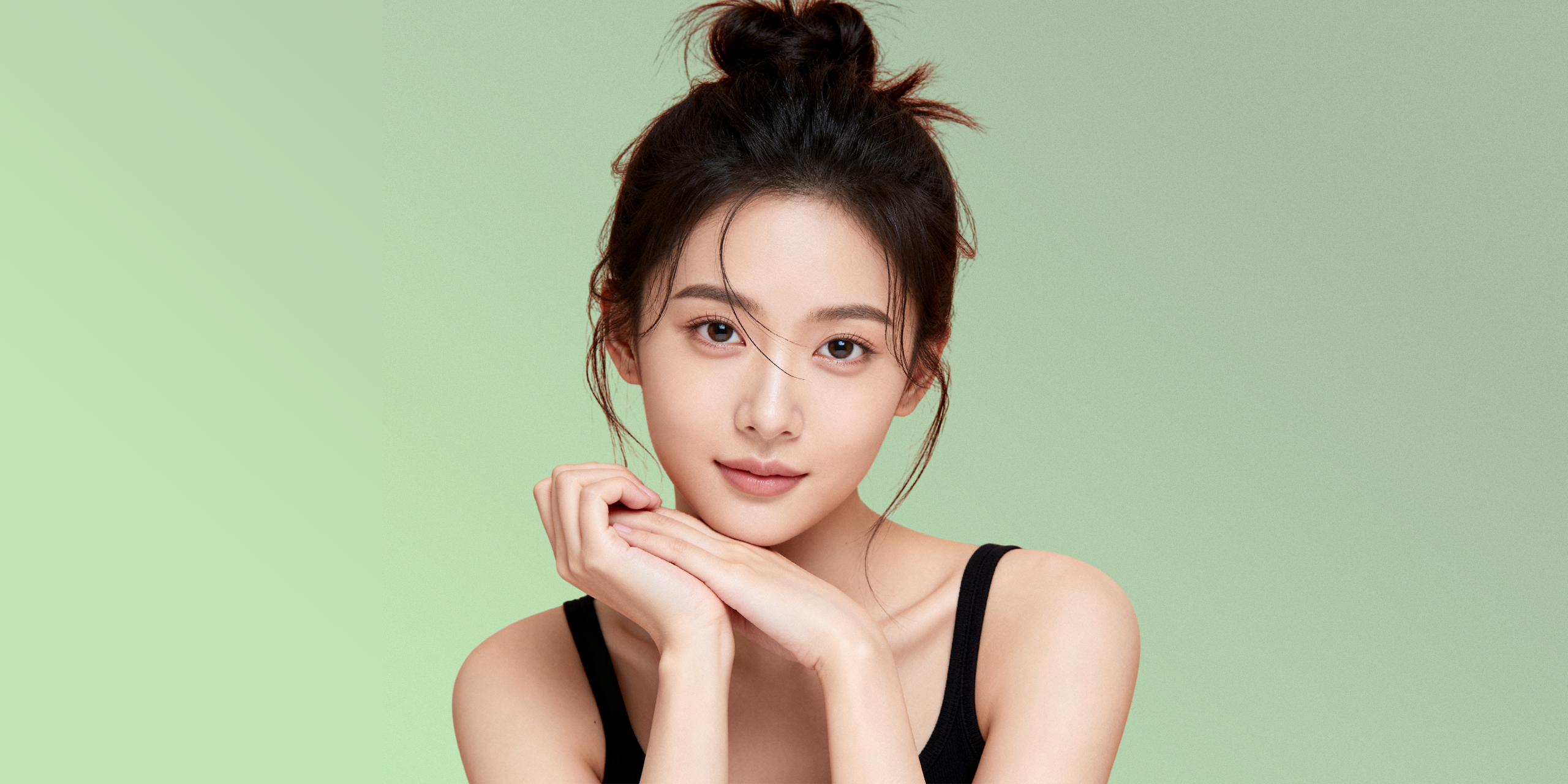 Retrato editorial de una mujer con piel luminosa sobre fondo sage